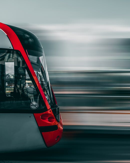 A front-facing view of a modern red and white moving van or minibus with large windows, parked outdoors on a paved surface, with a blurred background indicating motion or speed, suggesting a quick relocation or transport service. The van is clean and well-maintained, and the lighting highlights its sleek exterior. This image is associated with house removals and furniture transport, as part of the logistics involved in home relocation services. The scene emphasizes the vehicle's role in loading or transporting household items, reflecting the services provided by Man with Van Camberwell in facilitating efficient and prompt moves within the Camberwell area.